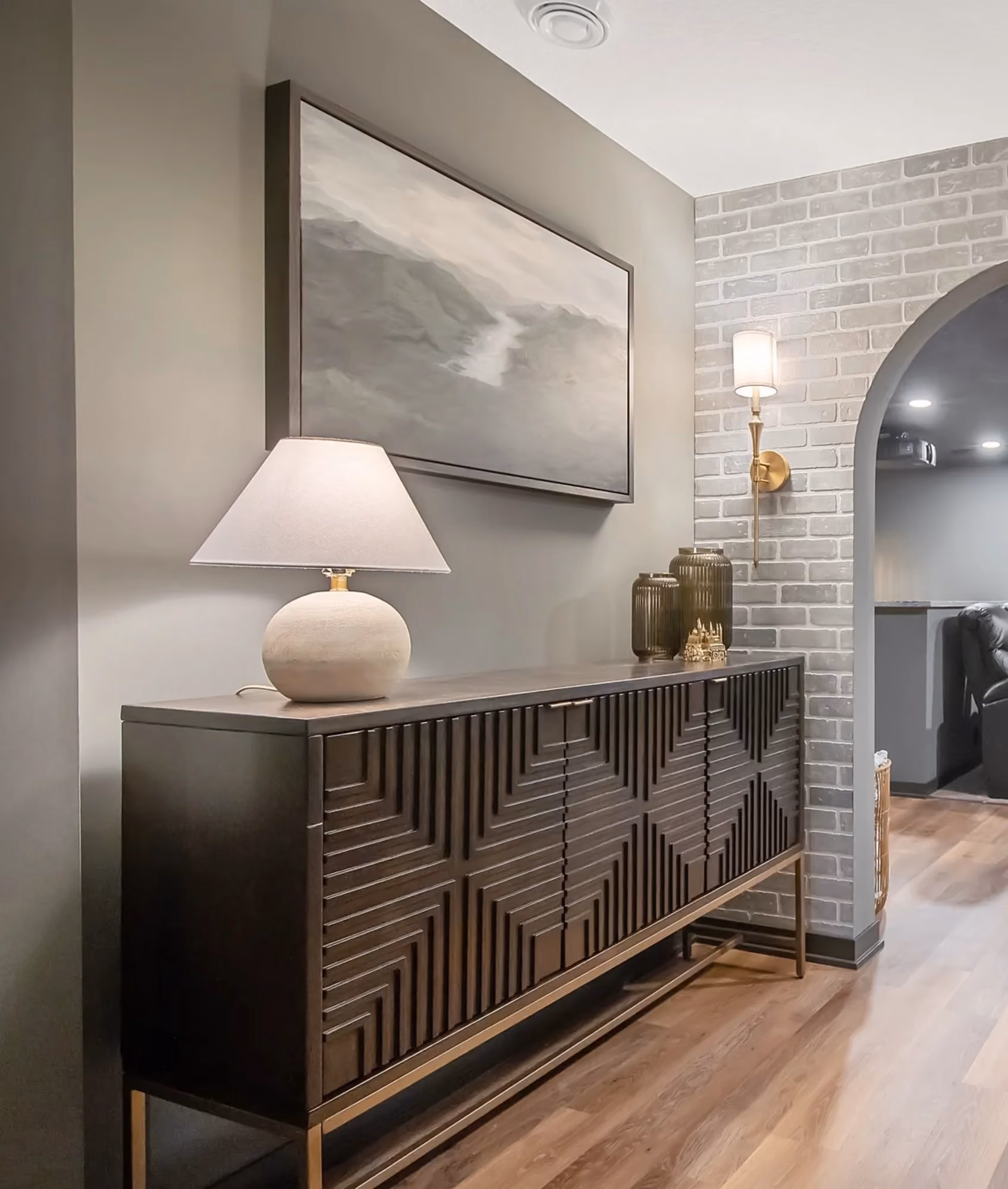 Hallway with console table, arched doorway, and brick wall