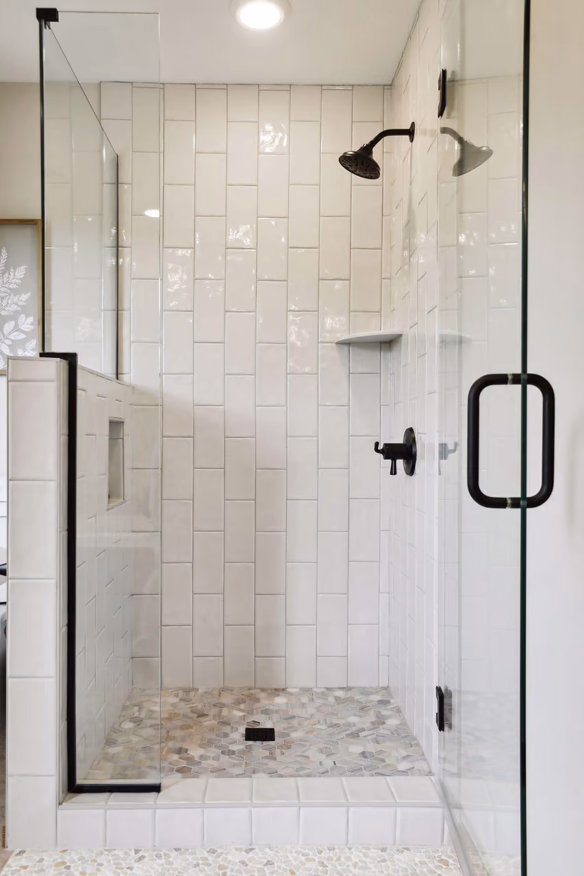 Glass shower enclosure with tiled walls and black fixtures