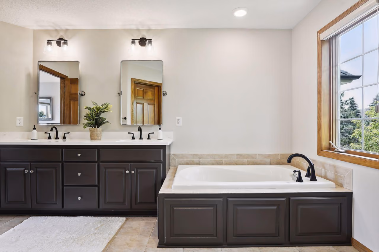 Double-sink bathroom vanity with dark cabinets and framed mirrors