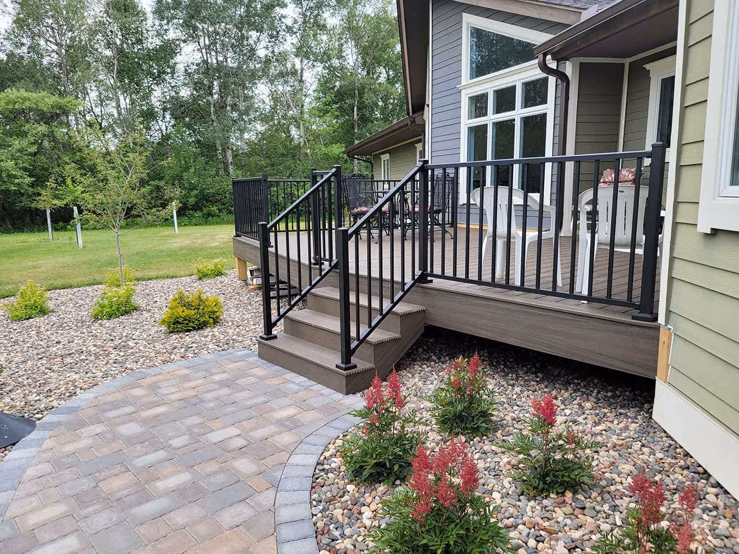 Front porch steps with black railings and flower bed