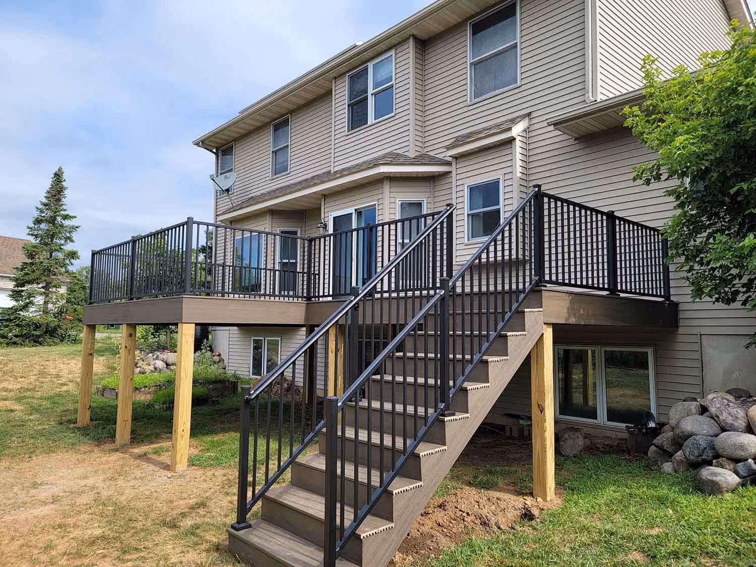 Elevated backyard deck with black staircase and railing