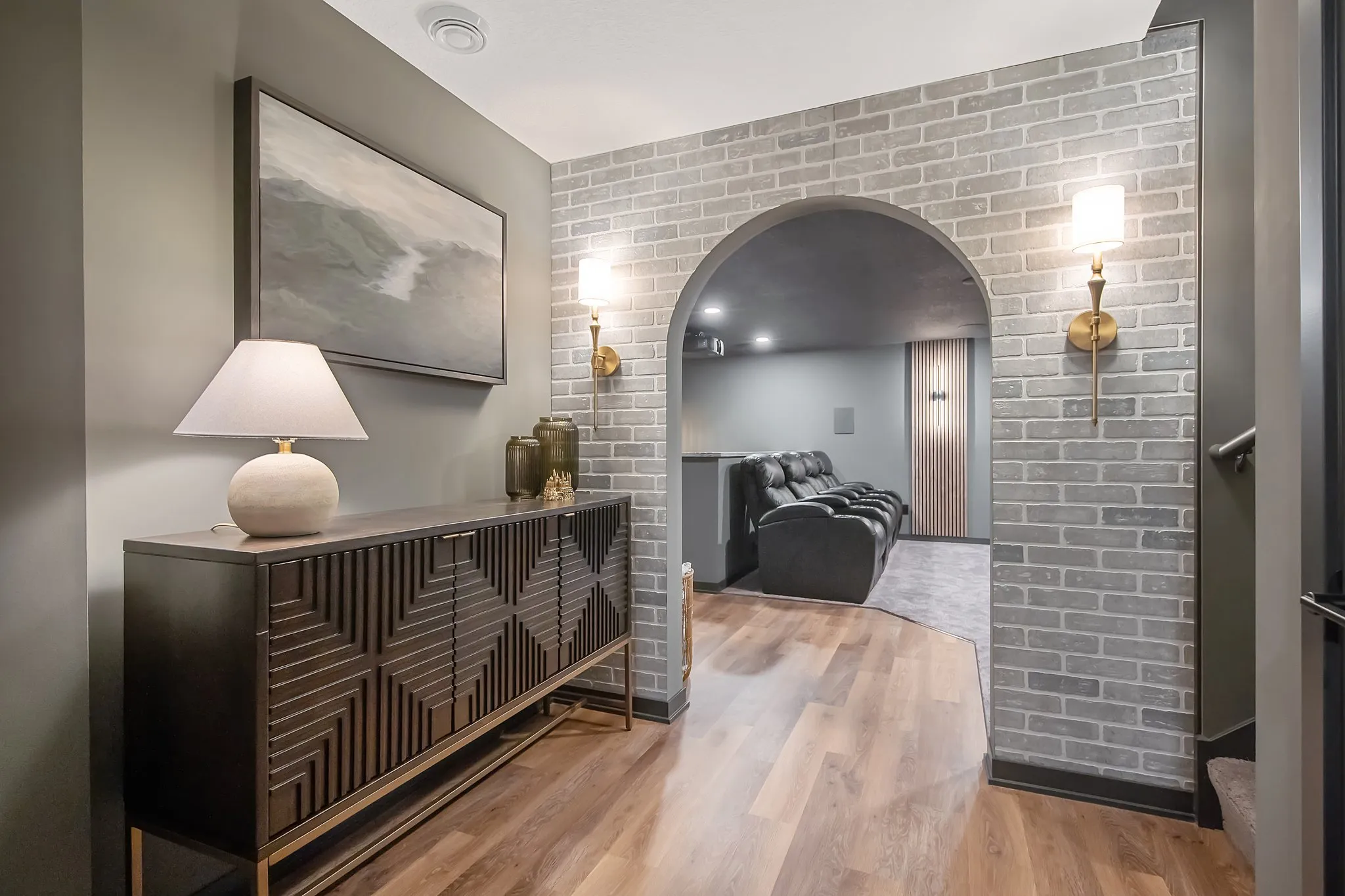 Hallway with console table, arched doorway, and brick wall