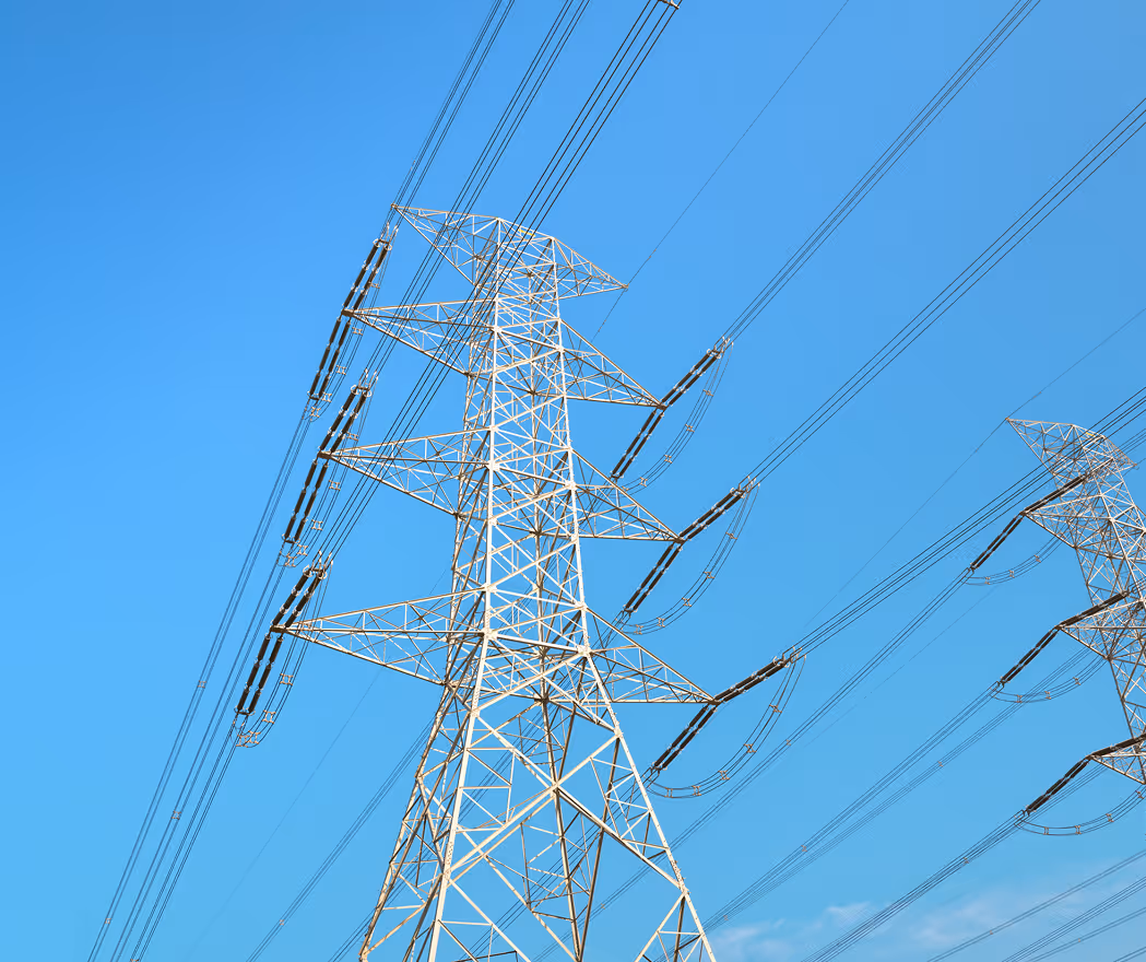 High-voltage electricity transmission towers with wires against a clear blue sky.