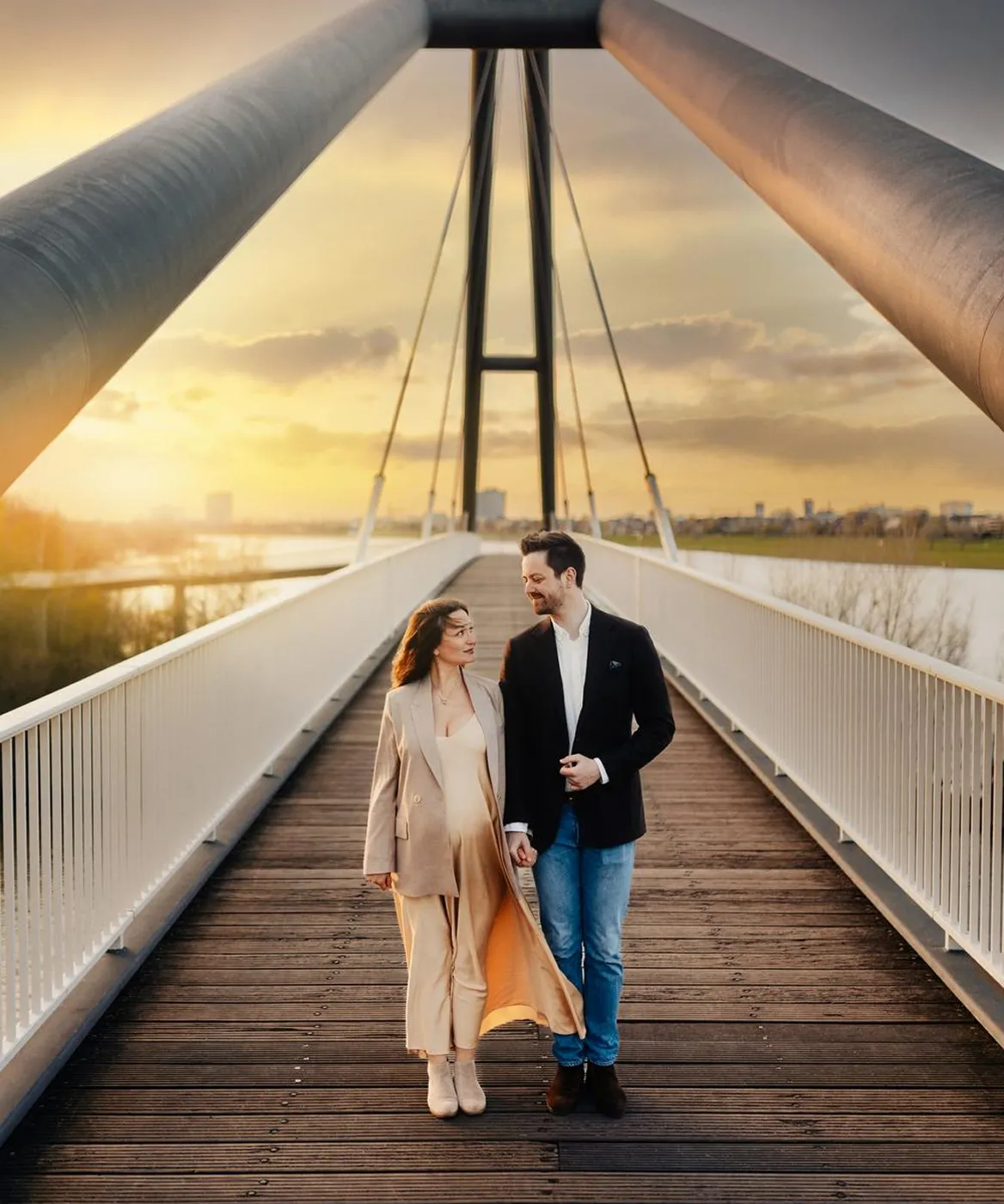 Couple holding hands and walking on a modern suspension bridge at sunset.