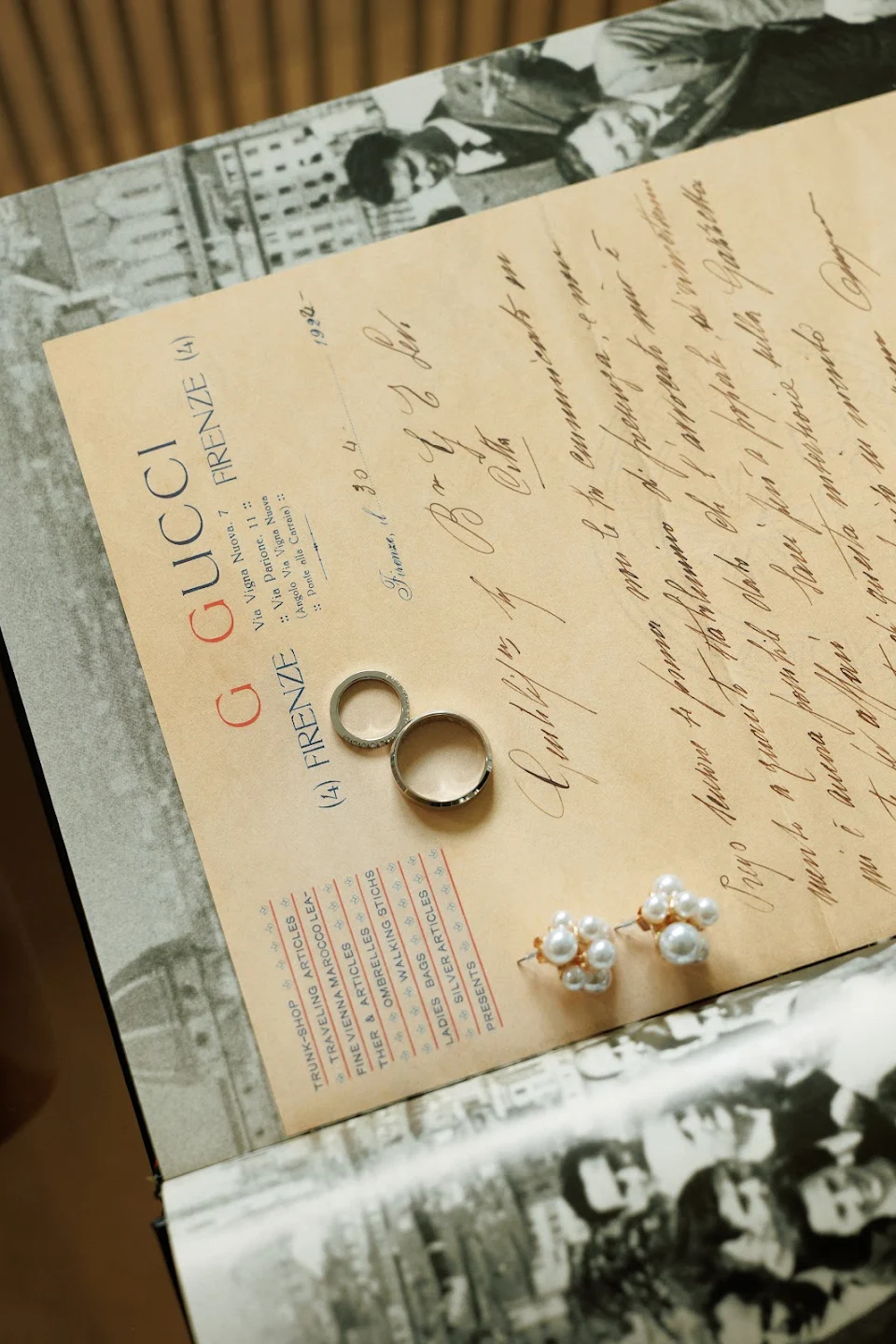 Two rings and a pair of pearl cluster earrings placed on a vintage Gucci Firenze letter with handwritten script.