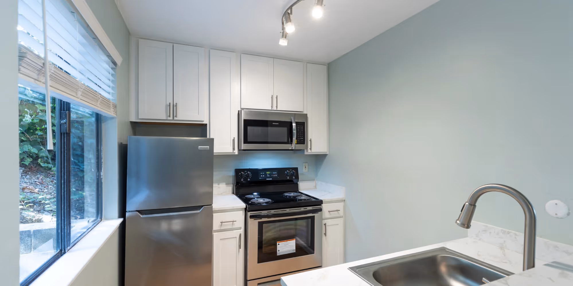 Kitchen with white cabinets and stainless appliances featuring a large window