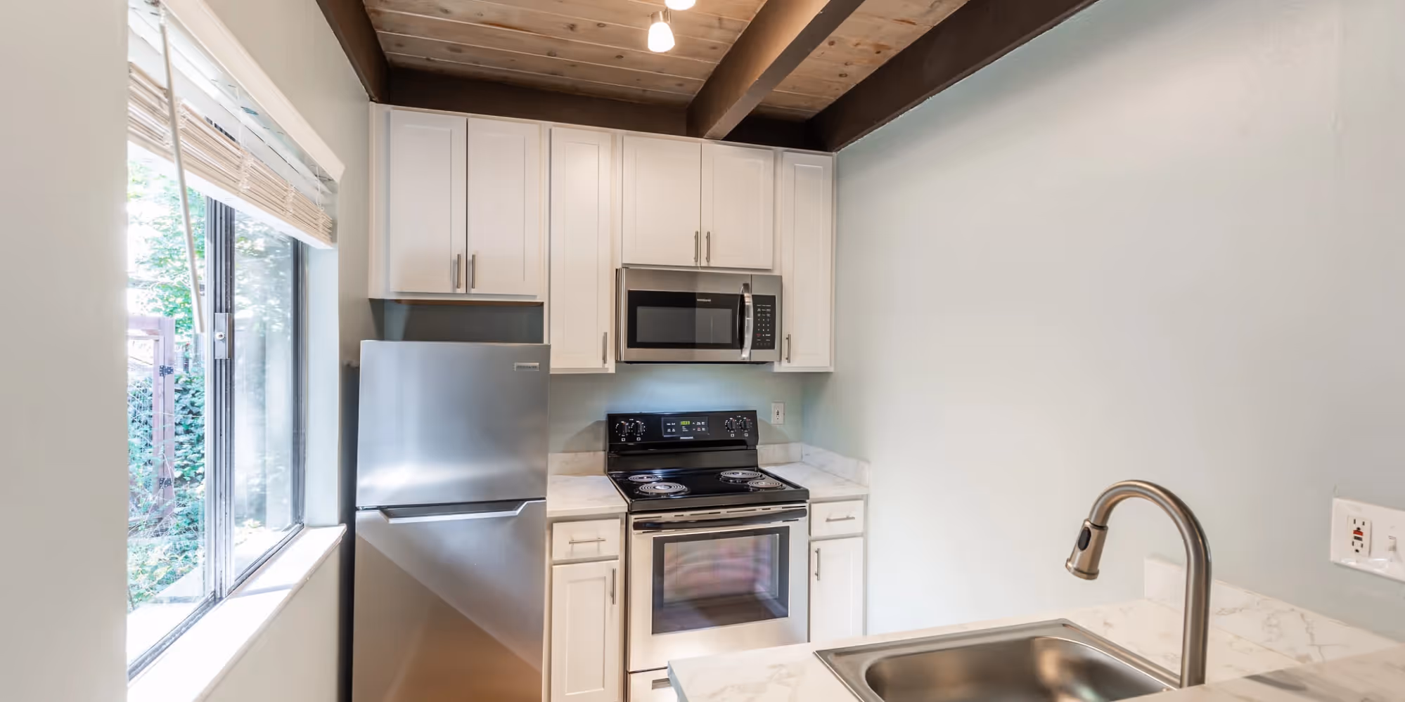 Kitchen with white cabinets and stainless appliances featuring a large window