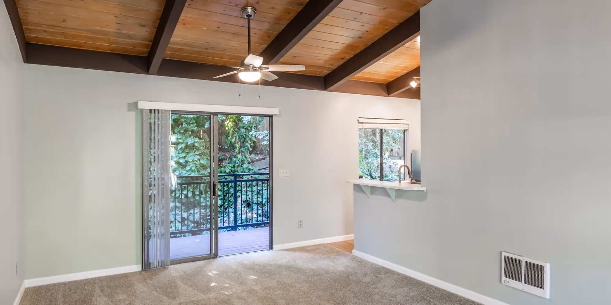 Wide view of unfurnished living and dining area with view of balcony doors