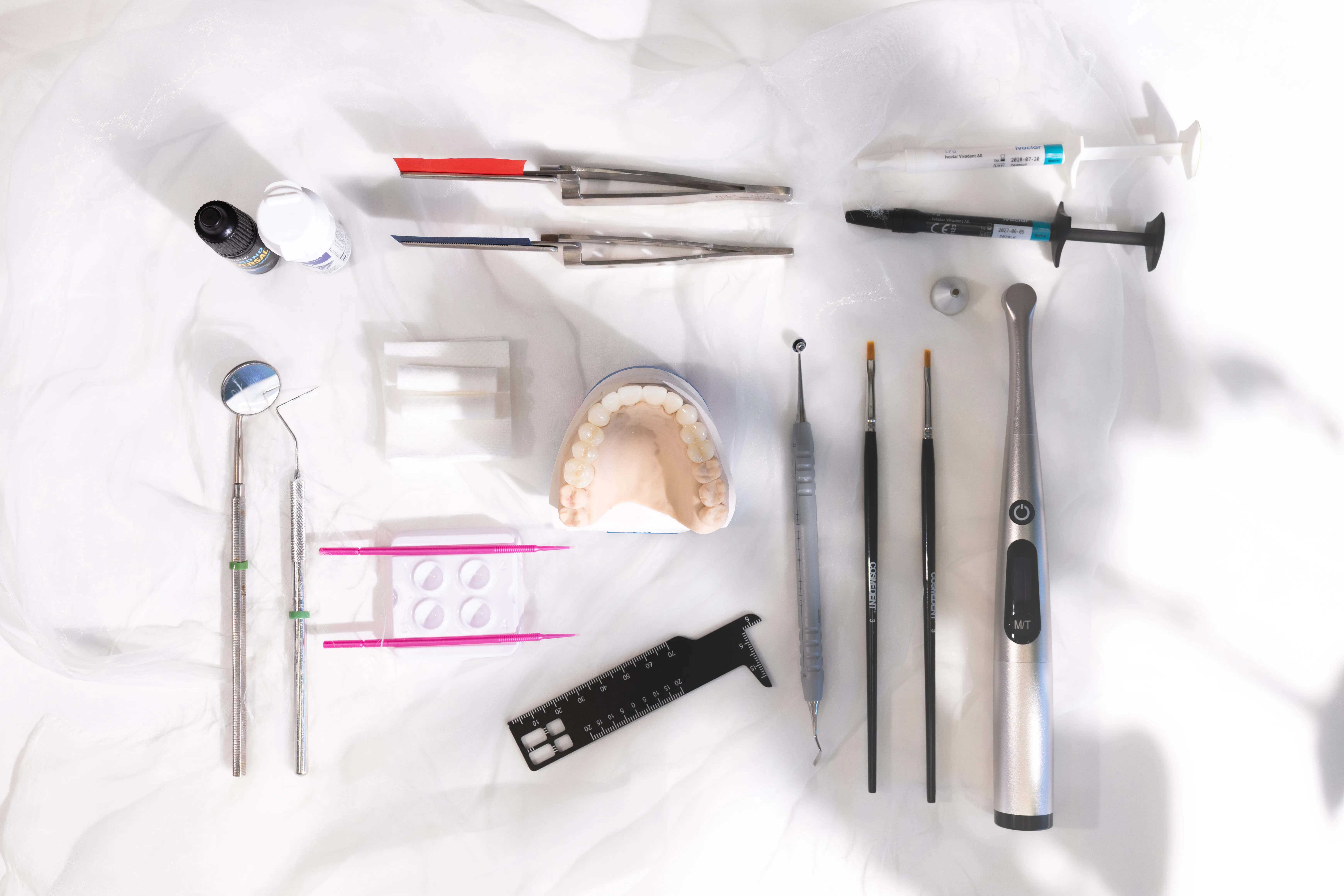 Overhead flat lay of cosmetic dentistry tools and a dental veneer model