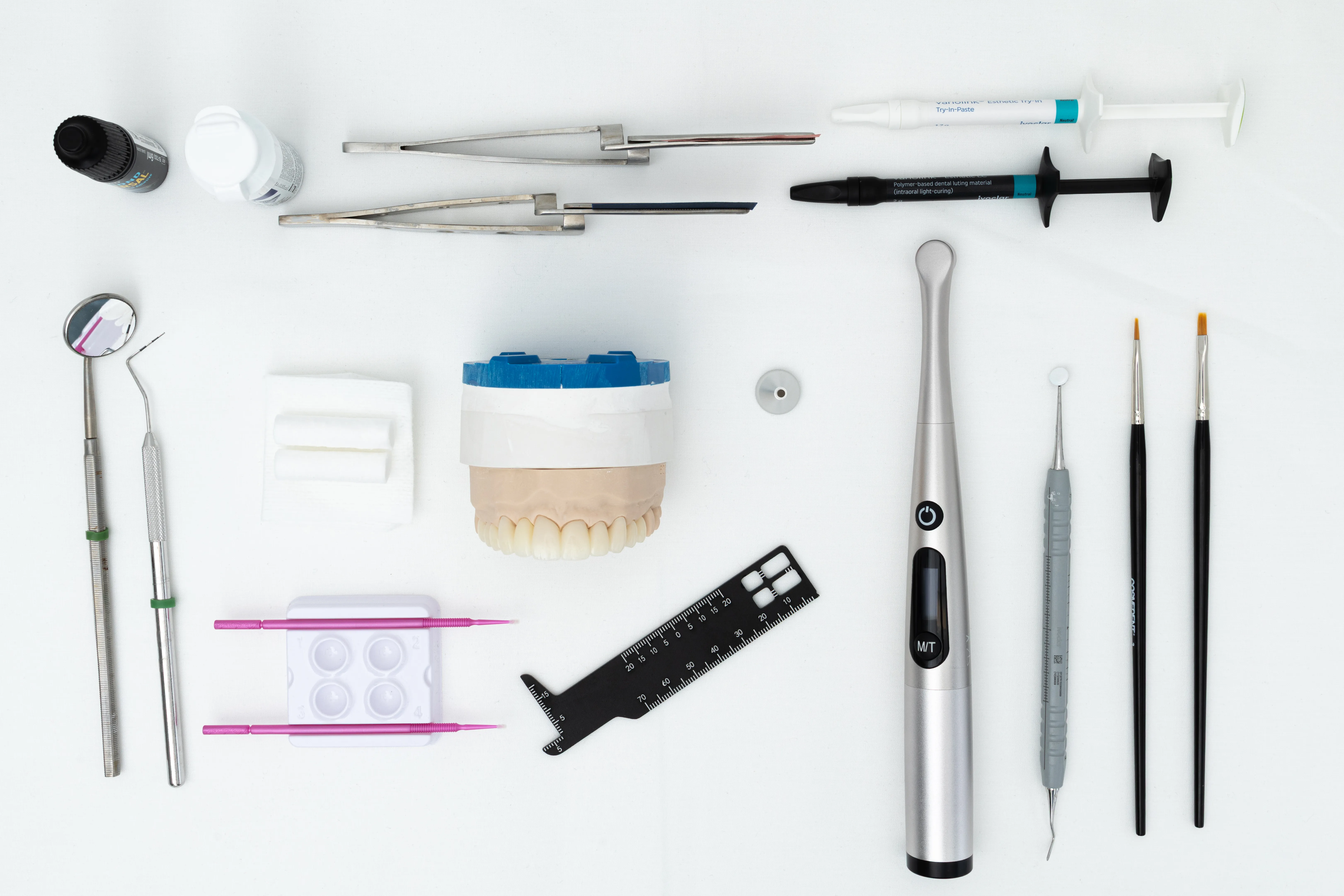 Flat lay of cosmetic dentistry tools and a veneer model