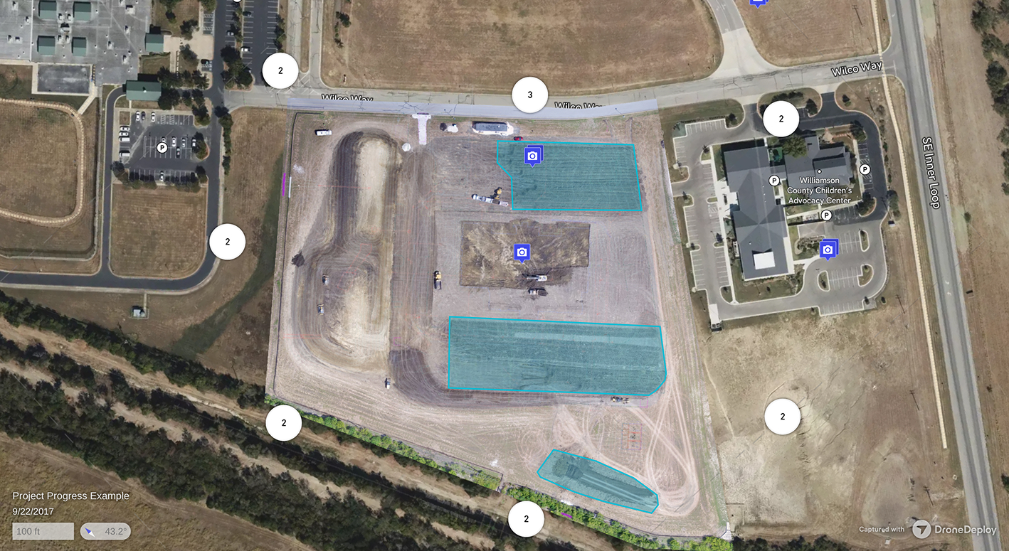 Aerial view of a construction site with three blue highlighted areas, nearby parking lots, and buildings including Williamson County Children's Advocacy Center.