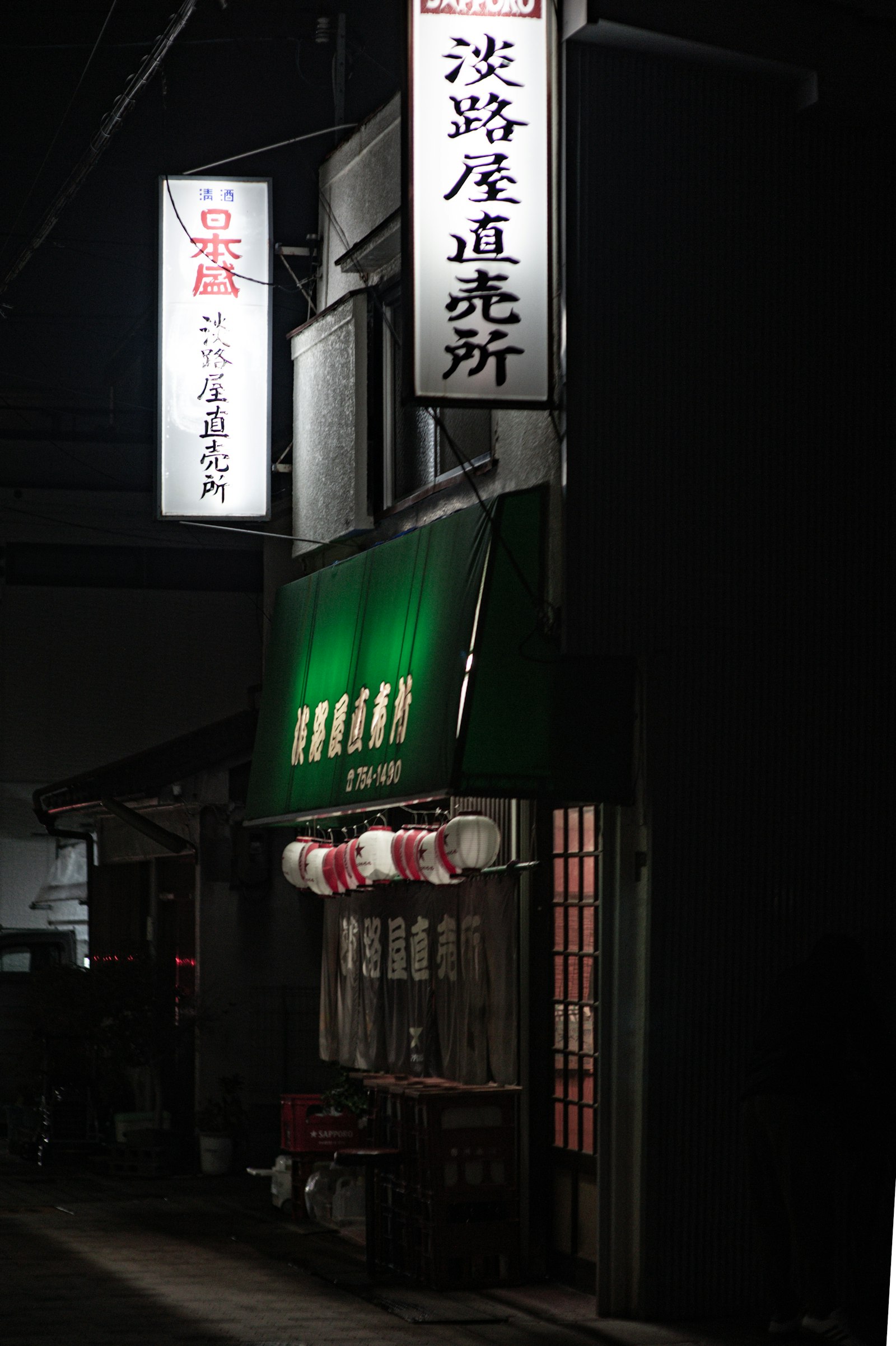 Japanese izakaya storefront glowing at night with traditional red lanterns