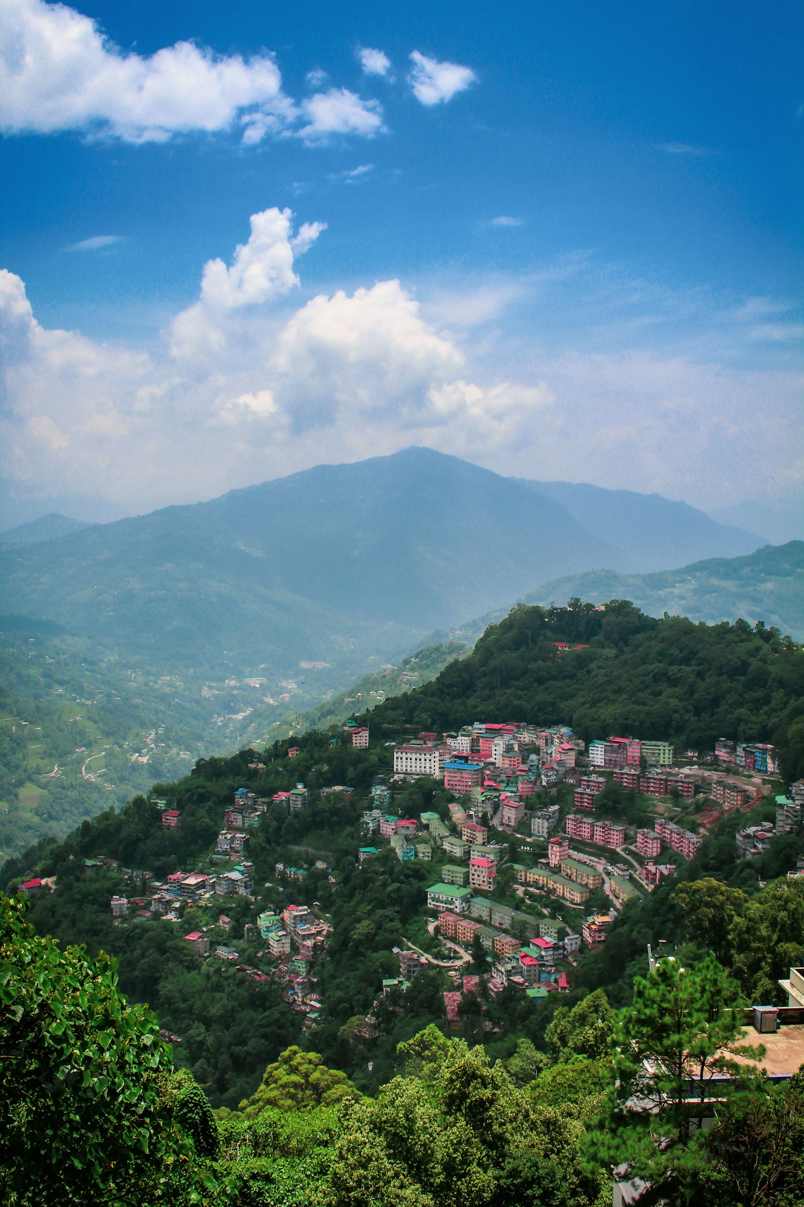Hillside settlement amid lush Himalayan mountains in Sikkim under a bright blue sky