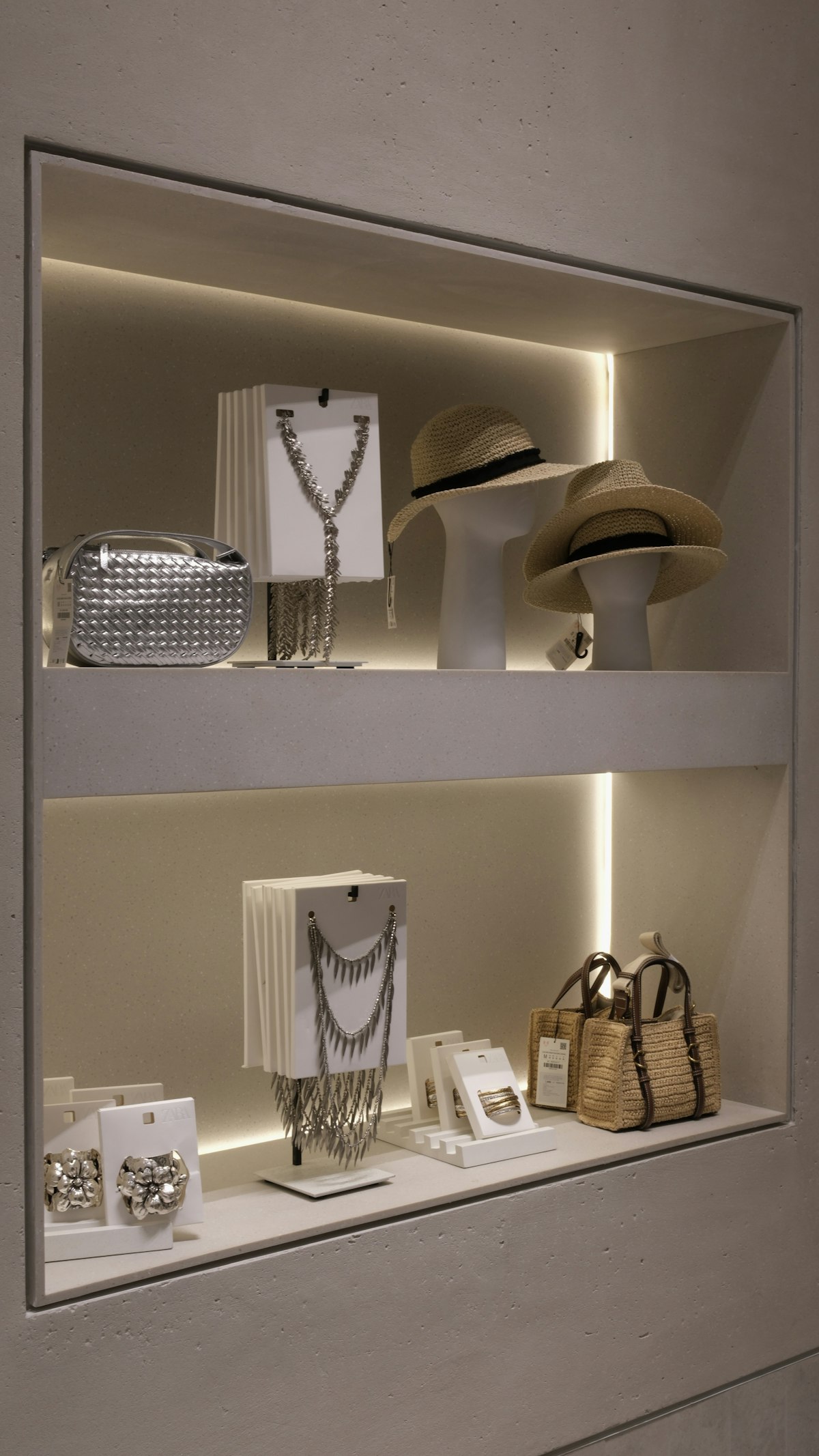 Luxury jewellery and designer handbags displayed on an illuminated shelf