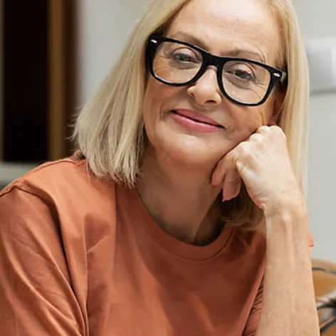 A happy woman leaning on her hand with a smile.