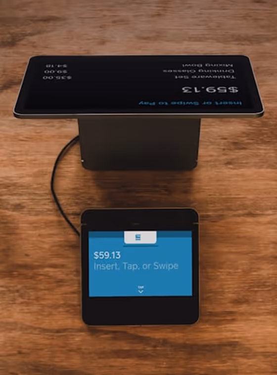 Payment terminal on a wooden surface showing $59.13 with insert, tap, or swipe options.