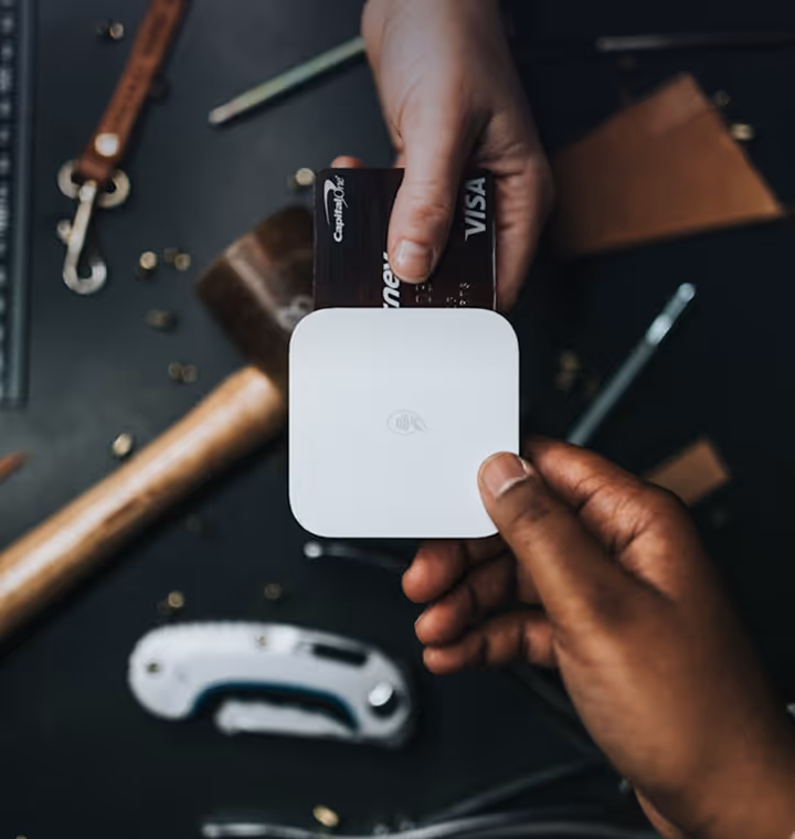 Hands holding a white card reader as a credit card is inserted for payment.