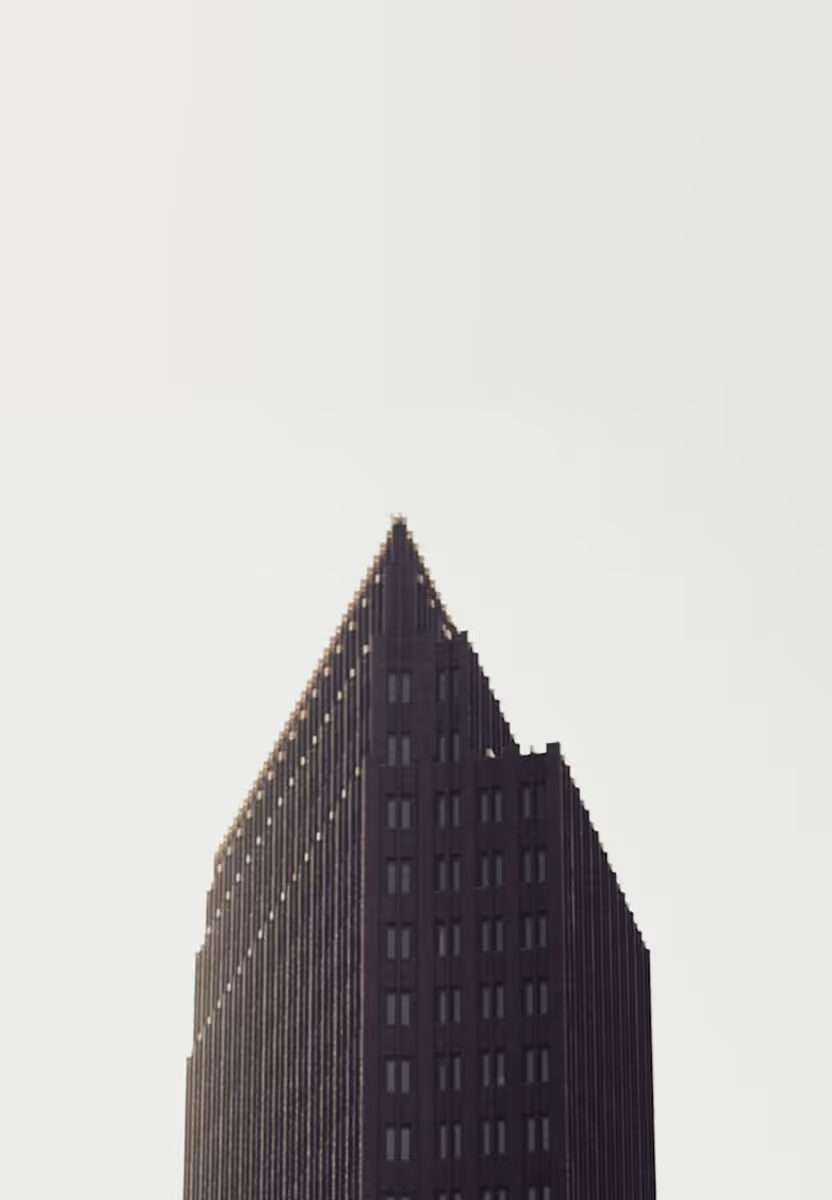 Dark triangular-shaped skyscraper against a light gray sky background.