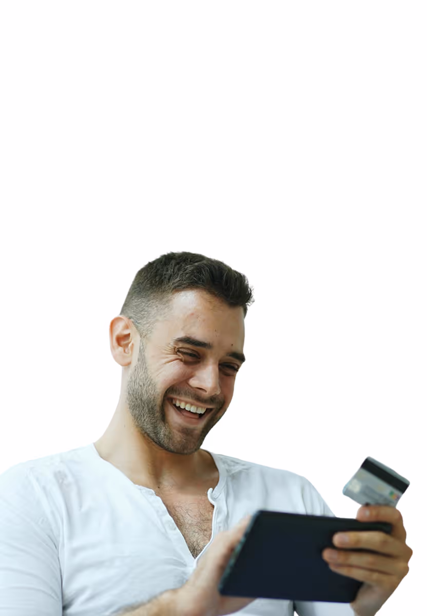 Smiling man in white shirt holding a credit card and using a digital tablet.