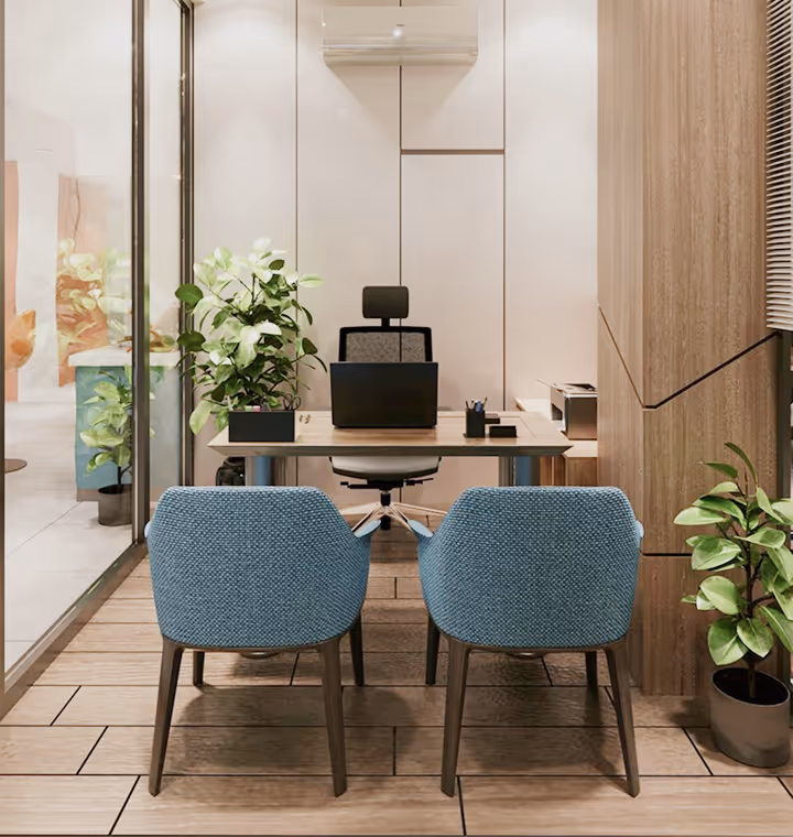 Modern office with a desk, black office chair, two blue guest chairs, plants, and a laptop.