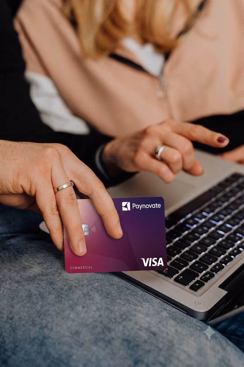 Hands holding a credit card and typing on a laptop keyboard for online payment.