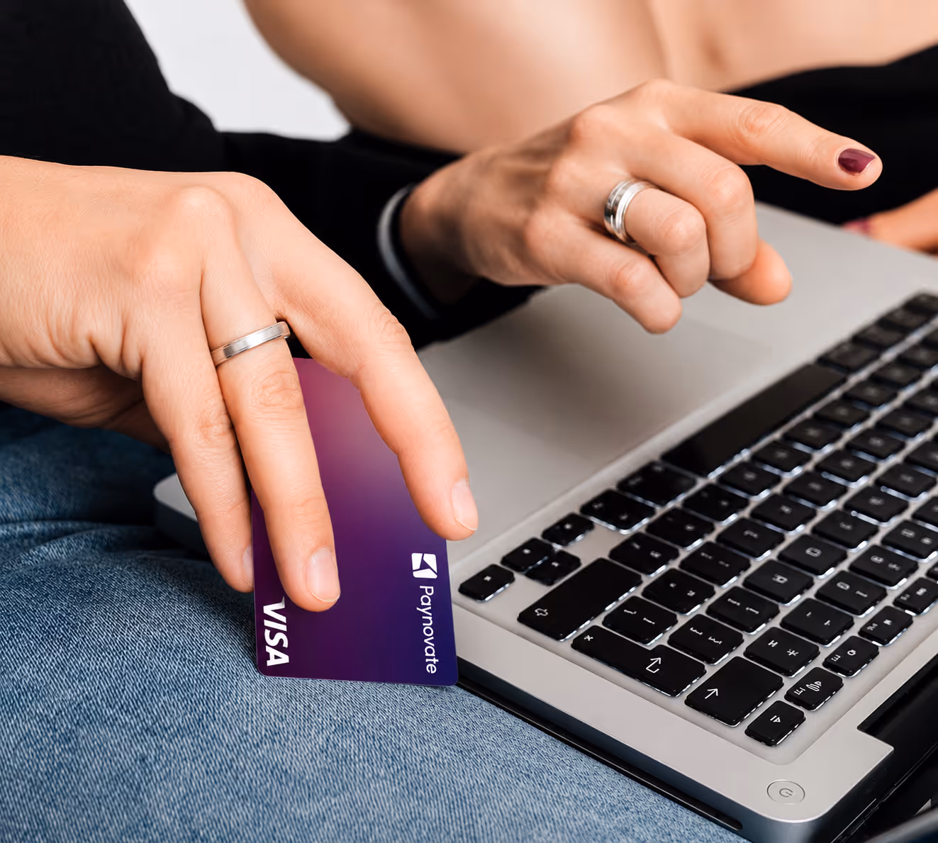 Hands holding a credit card and typing on a laptop keyboard for online payment.