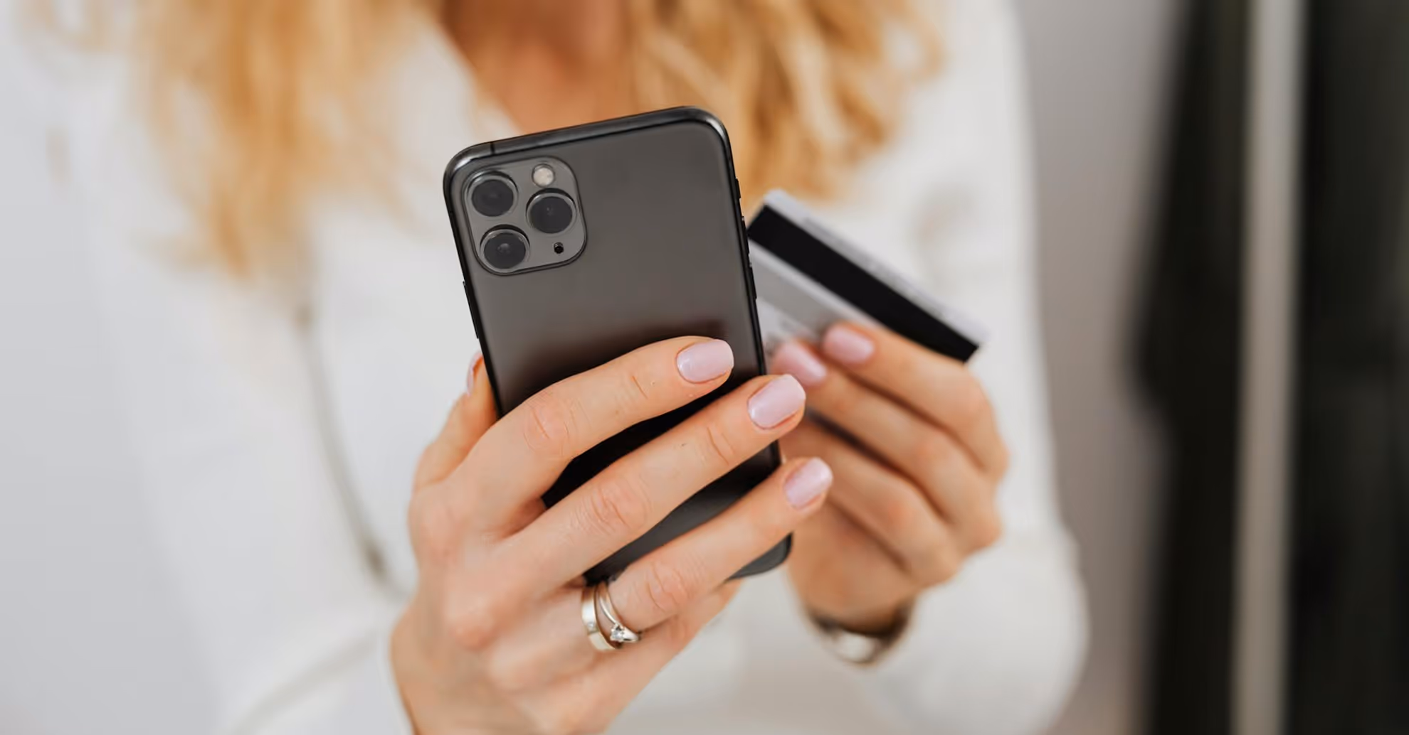 Person holding a black smartphone in one hand and a credit card in the other.