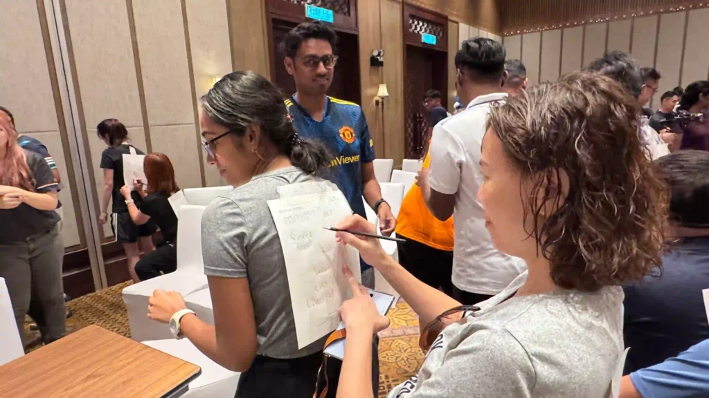 Two individuals from Vision Building engage in a focused, collaborative activity in a crowded room. The moment of close connection and communication reflects the changing meaning of connection in the hybrid workplace.