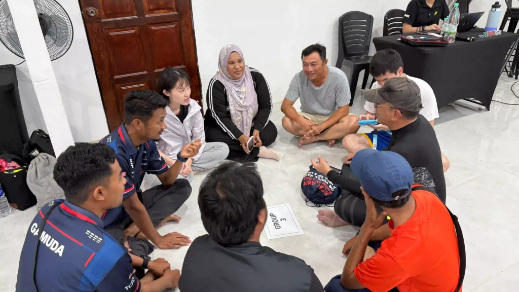 team members in vision building event are seated in a close circle on the floor, engaging in an open and authentic discussion. Their relaxed yet focused interaction highlights the genuine human connection being built, beyond just another event.