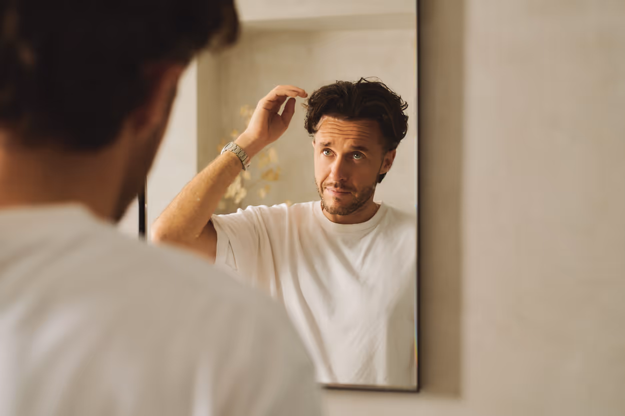 a man checking his hair in the mirror