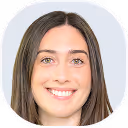 Porträt einer lächelnden jungen Frau mit langen braunen Haaren und hellem Teint vor weißem Hintergrund.