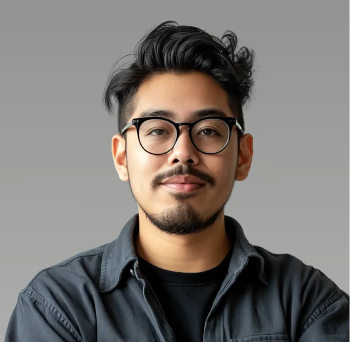 Young man with black hair, glasses, and facial hair wearing a dark button-up shirt over a black t-shirt.
