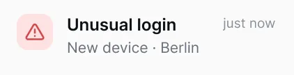 Notification alert with a red warning triangle icon and text 'Unusual login just now, New device, Berlin'.