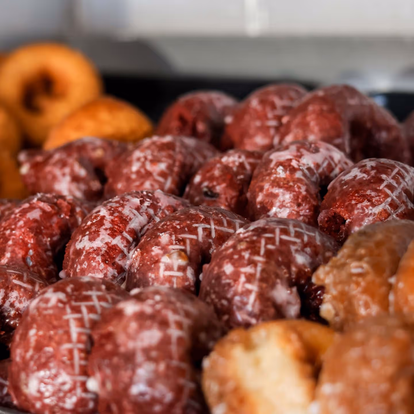 Close-up of glazed red velvet and plain donuts arranged closely together.