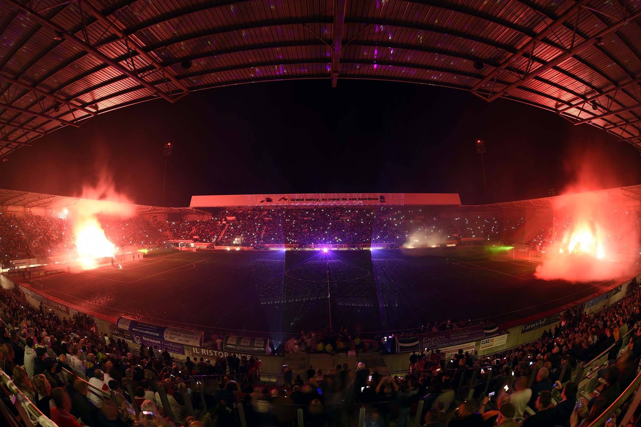 Milliers de supporters brandissant torches et lumières dans le stade AS Nancy lors d'un spectacle pyrotechnique événementiel Wagnon Events