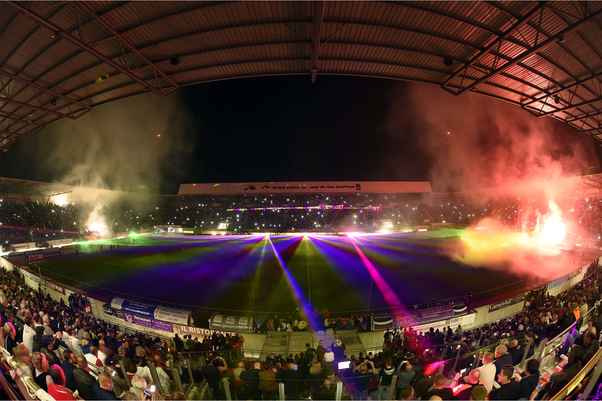 Stade de football AS Nancy plein de spectateurs illuminé par des lasers colorés et de la fumée lors d'un spectacle événementiel nocturne Wagnon Events