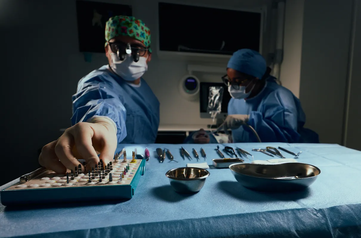 Deux chirurgiens en tenue stérile préparant des outils médicaux sur une table avant une opération.