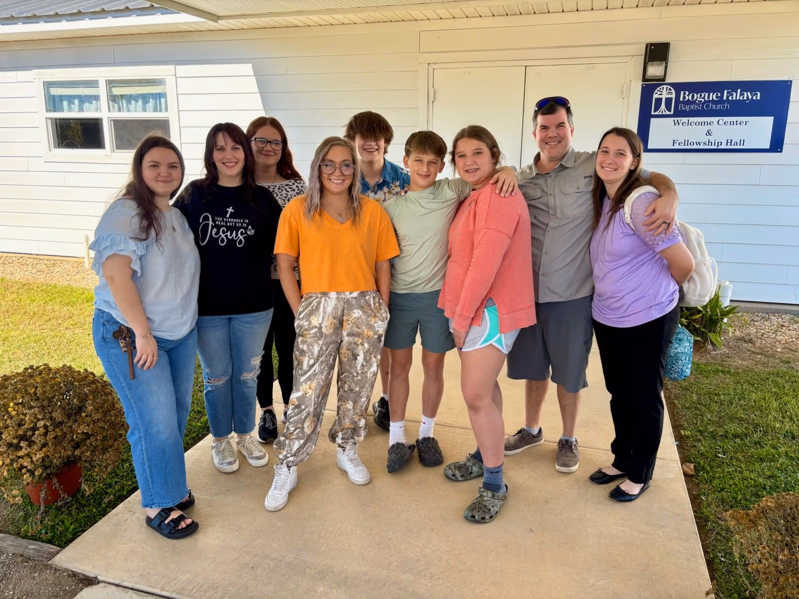 Group of nine people smiling outside Bogue Falaya Baptist Church Welcome Center & Fellowship Hall.