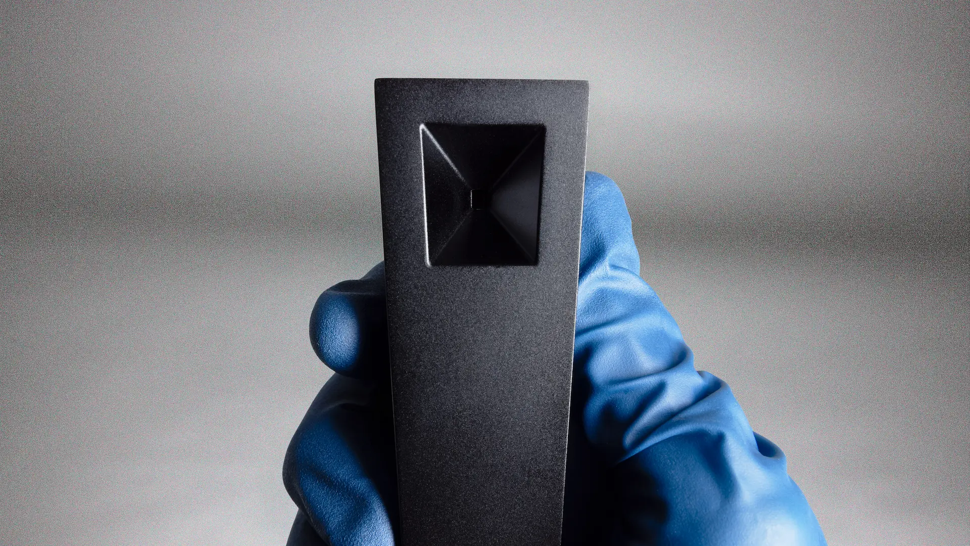 A gloved hand holds a Tempest pipe in Abyss (black anodized finish) showing off the square designed bowl