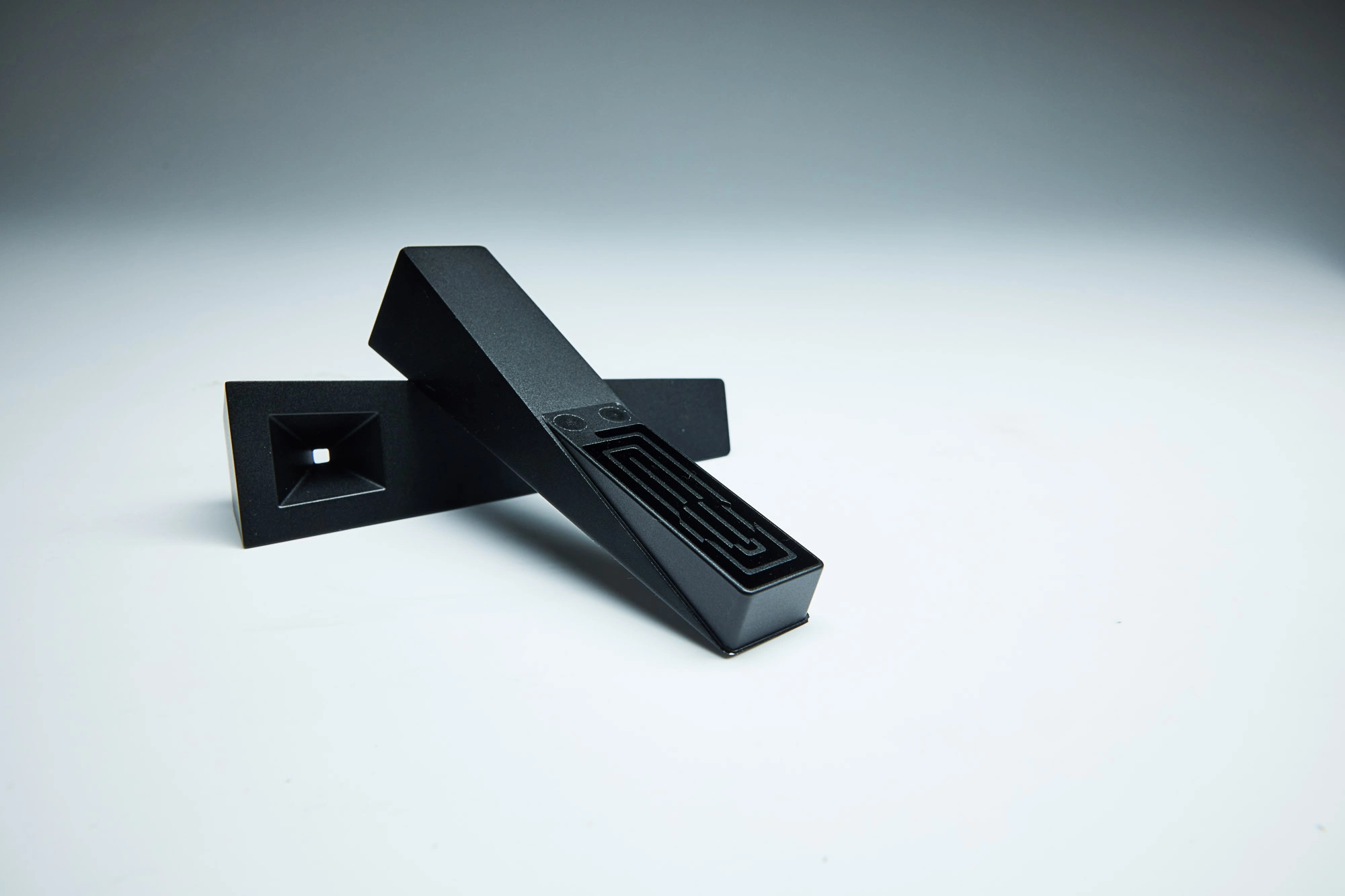 a modern designed Tempest smoking pipe with cooling pathway under the lid, with the lid laying across the base with cooling labyrinth underneath, shot in a moody studio