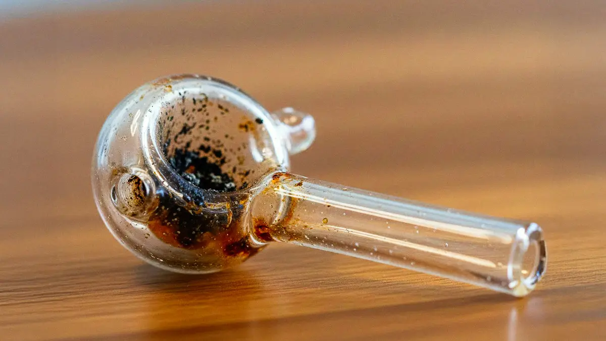 Residue buildup inside a glass pipe bend that is difficult to reach.