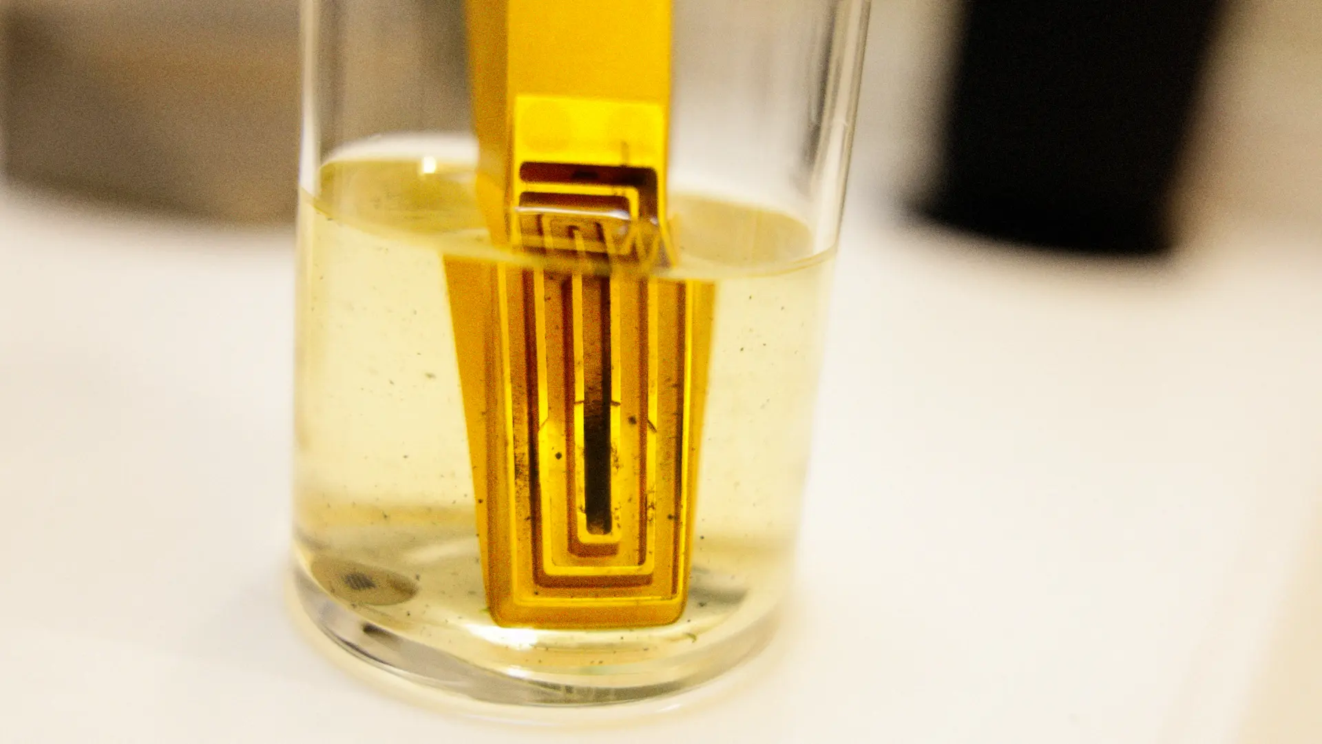 a designer metal pipe soaking in a glass of isopropyl alcohol