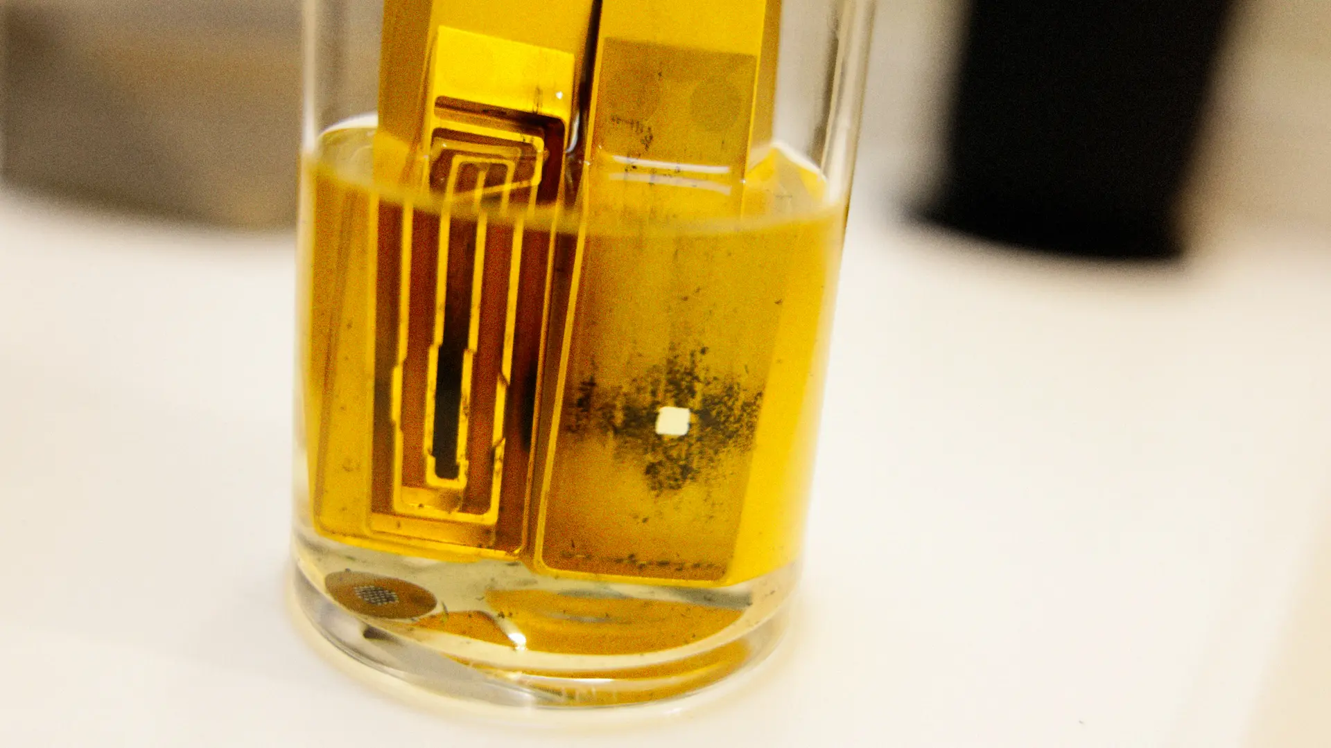 a designer metal pipe disassembled and soaking in a glass of isopropyl alcohol