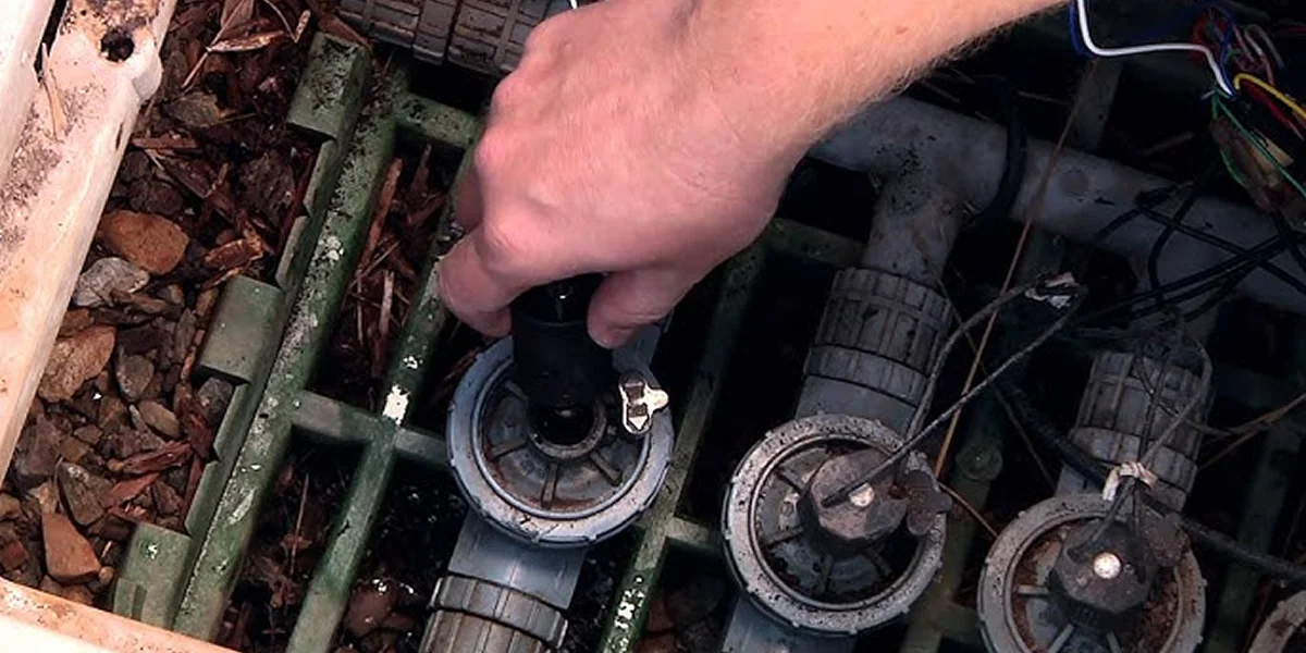 hand turning irrigation valve inside green box