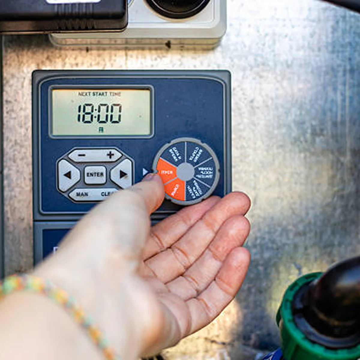 hand adjusting blue orange sprinkler timer controller