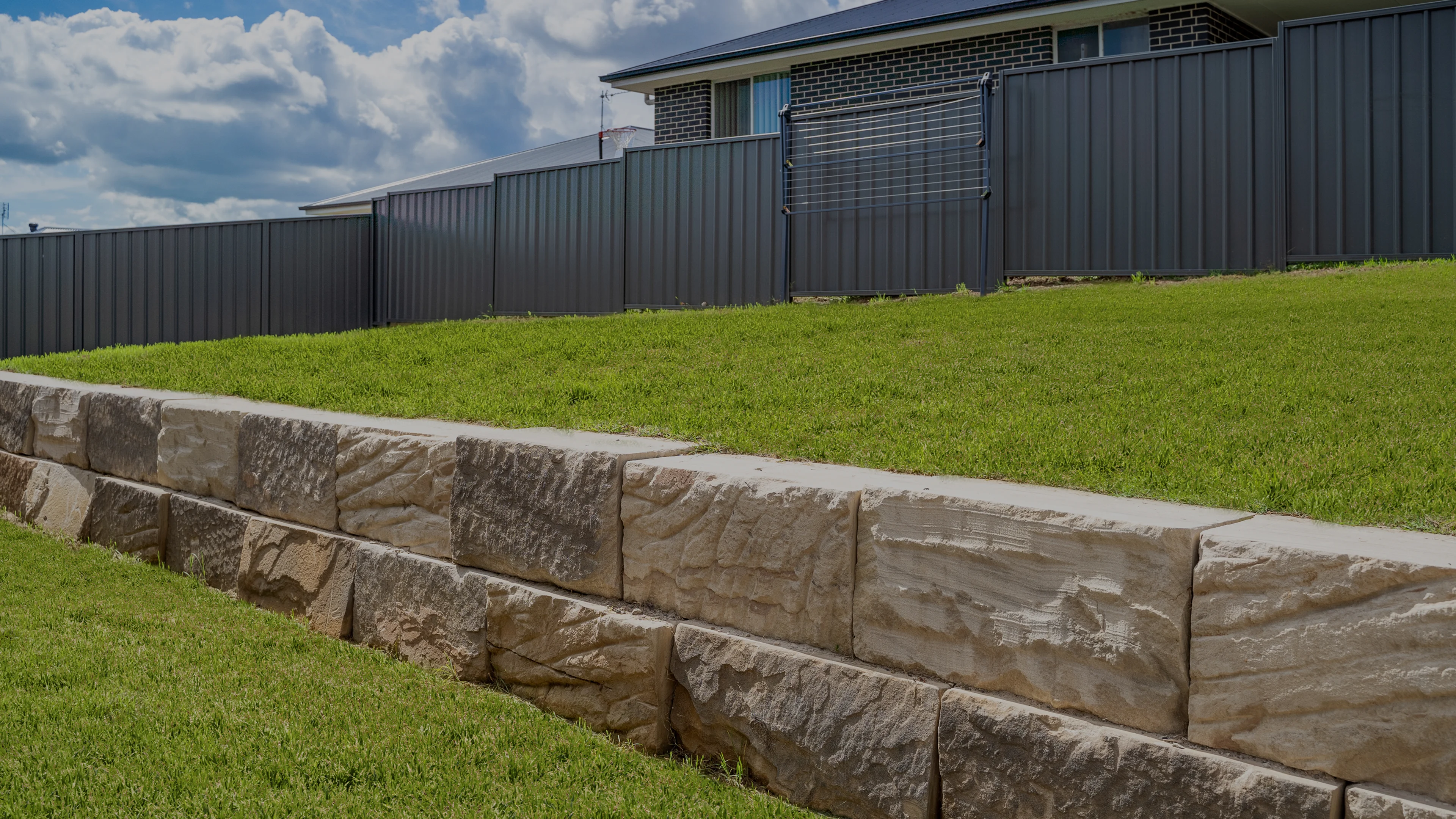 beige sandstone retaining wall green grass