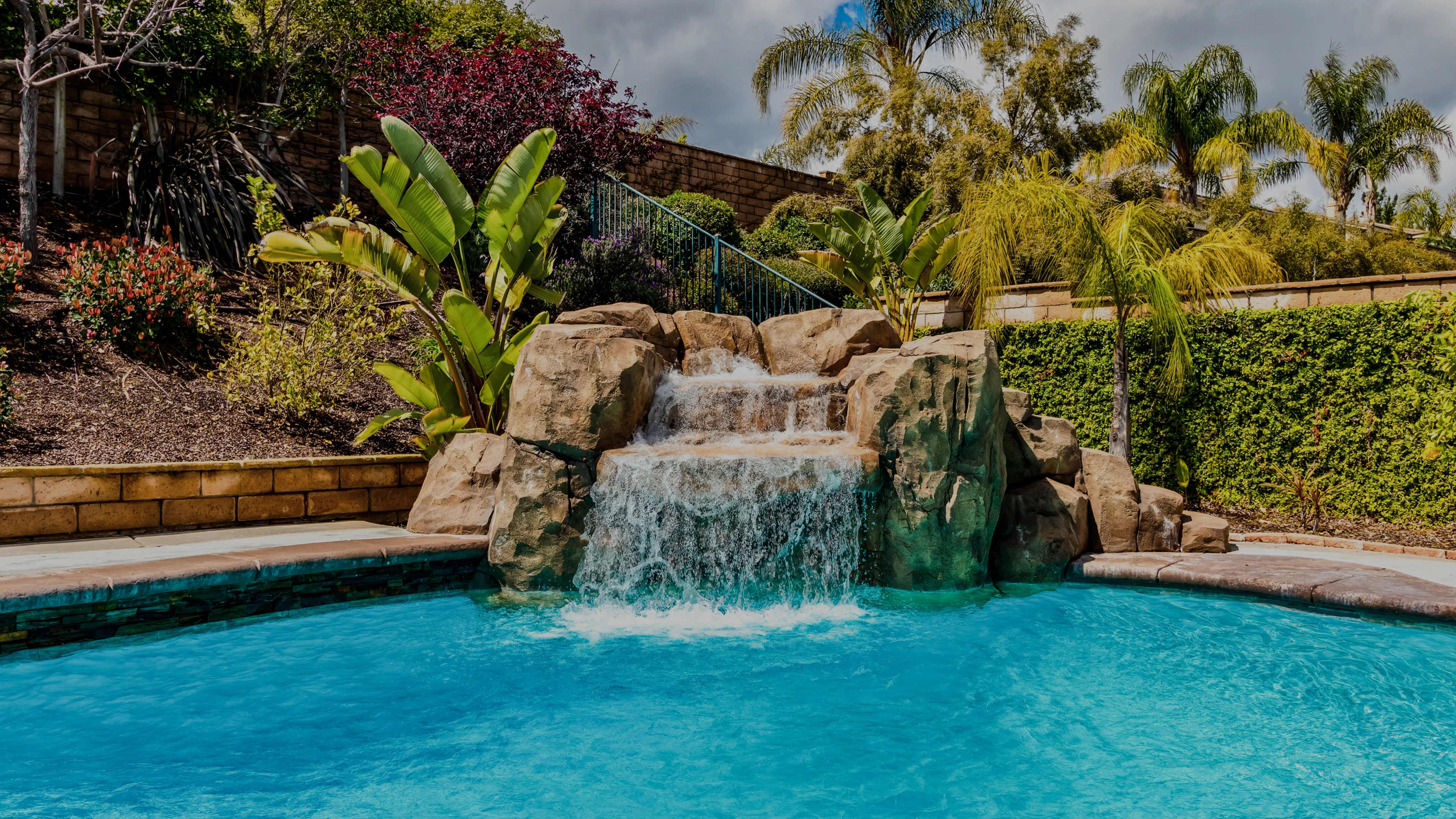 blue swimming pool rock waterfall tropical backyard