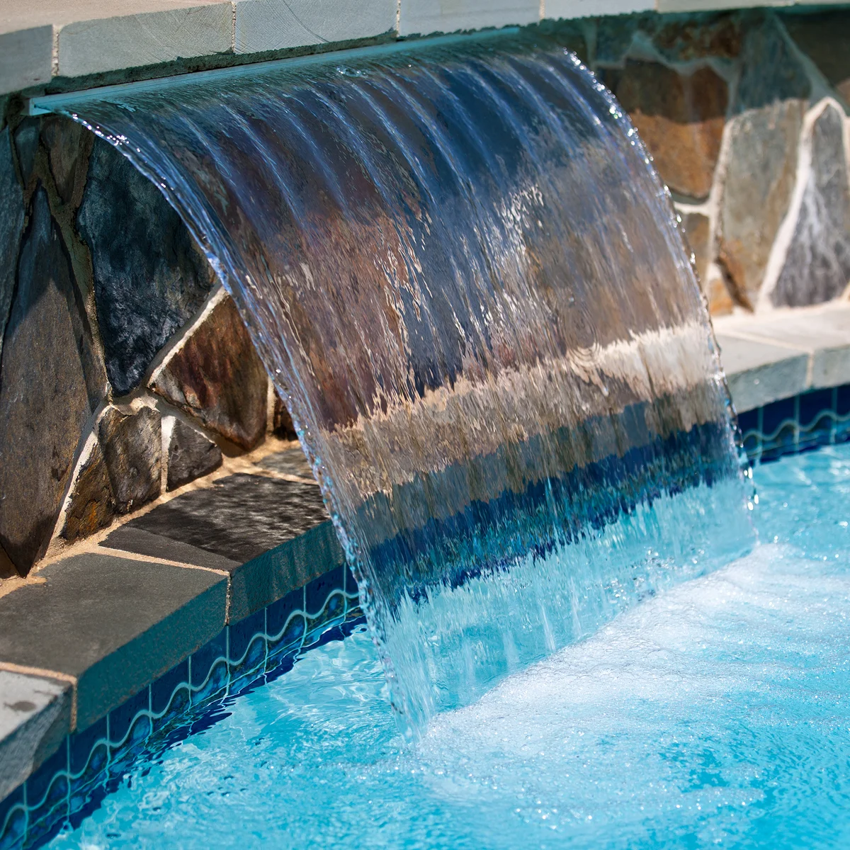 blue pool water waterfall stone ledge
