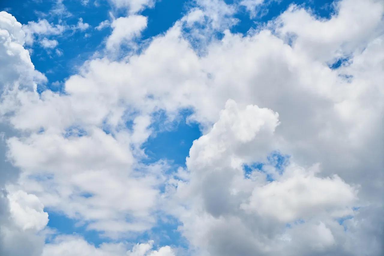 Bright blue sky scattered with fluffy white clouds.