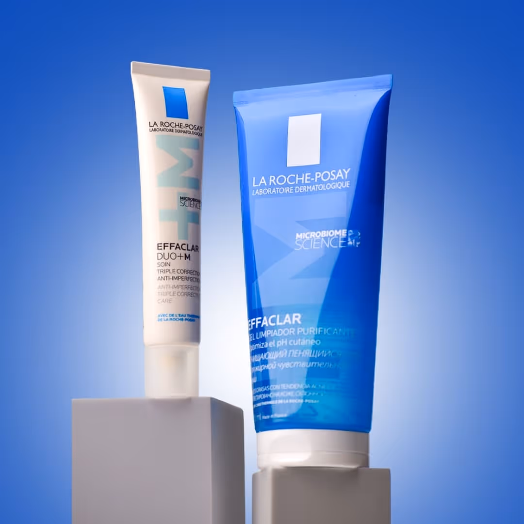 Two La Roche-Posay Effaclar skincare products, one white tube and one blue tube, displayed on gray stands against a blue gradient background.